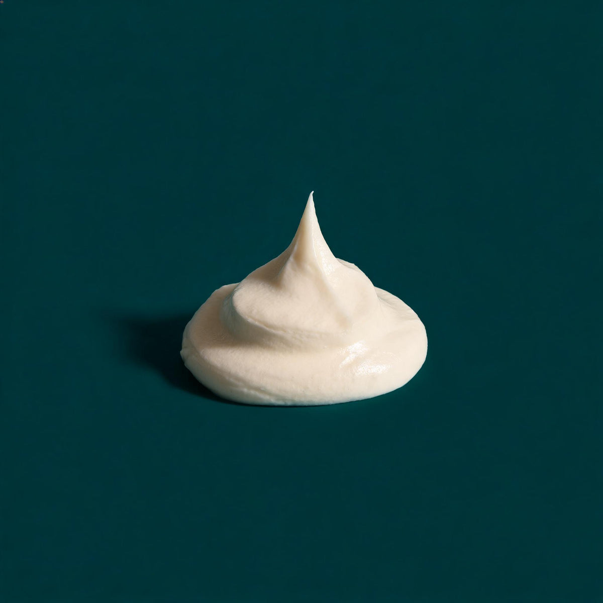 A peak of white firming cream on a deep teal background - Skingenetix firming and collagen range