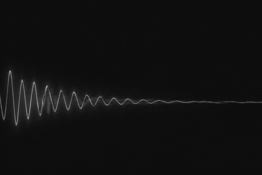 A wave of light losing height as it runs across a dark field