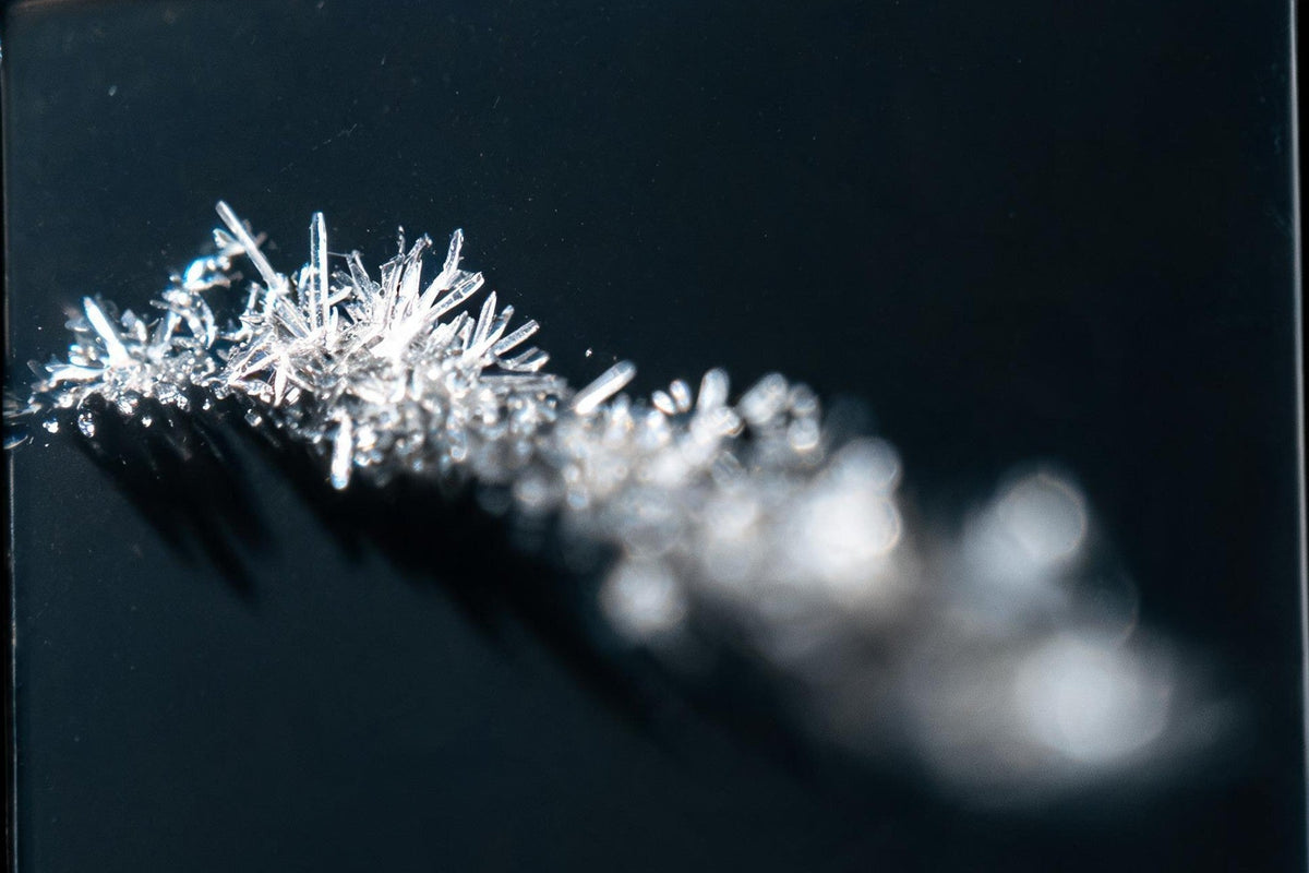 Clear peptide crystals on a dark glass slide, close up
