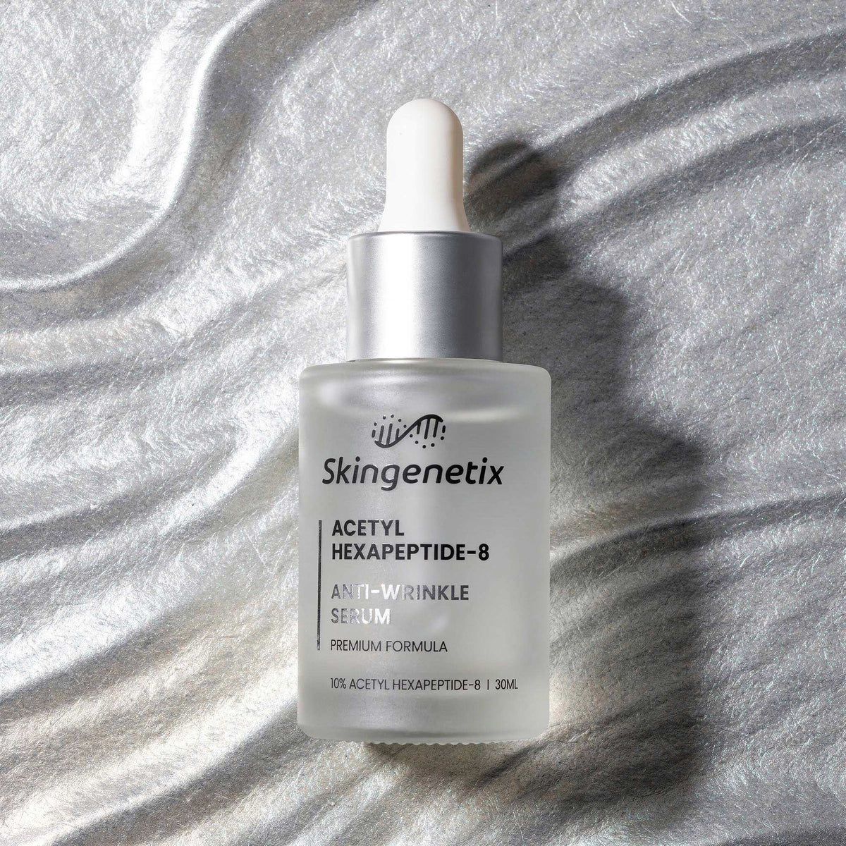 Skingenetix Acetyl Hexapeptide-8 Anti-Wrinkle Serum, 30ml - overhead view of the bottle on a rippled silver-grey surface