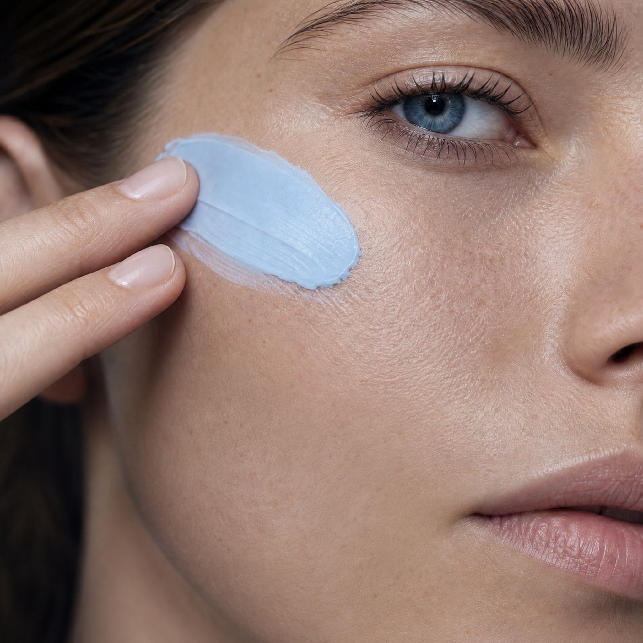 Skingenetix Copper Peptide (GHK-Cu) 2% Night Cream, 50ml - the pale blue cream smoothed onto a cheek