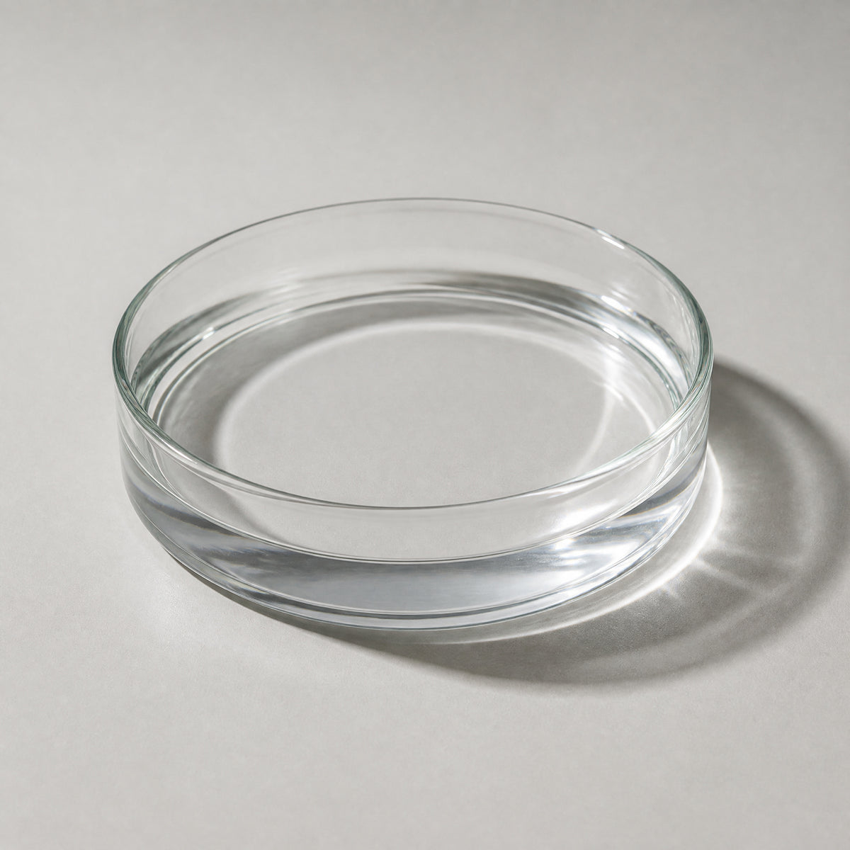 A glass petri dish of clear peptide solution on a pale grey surface