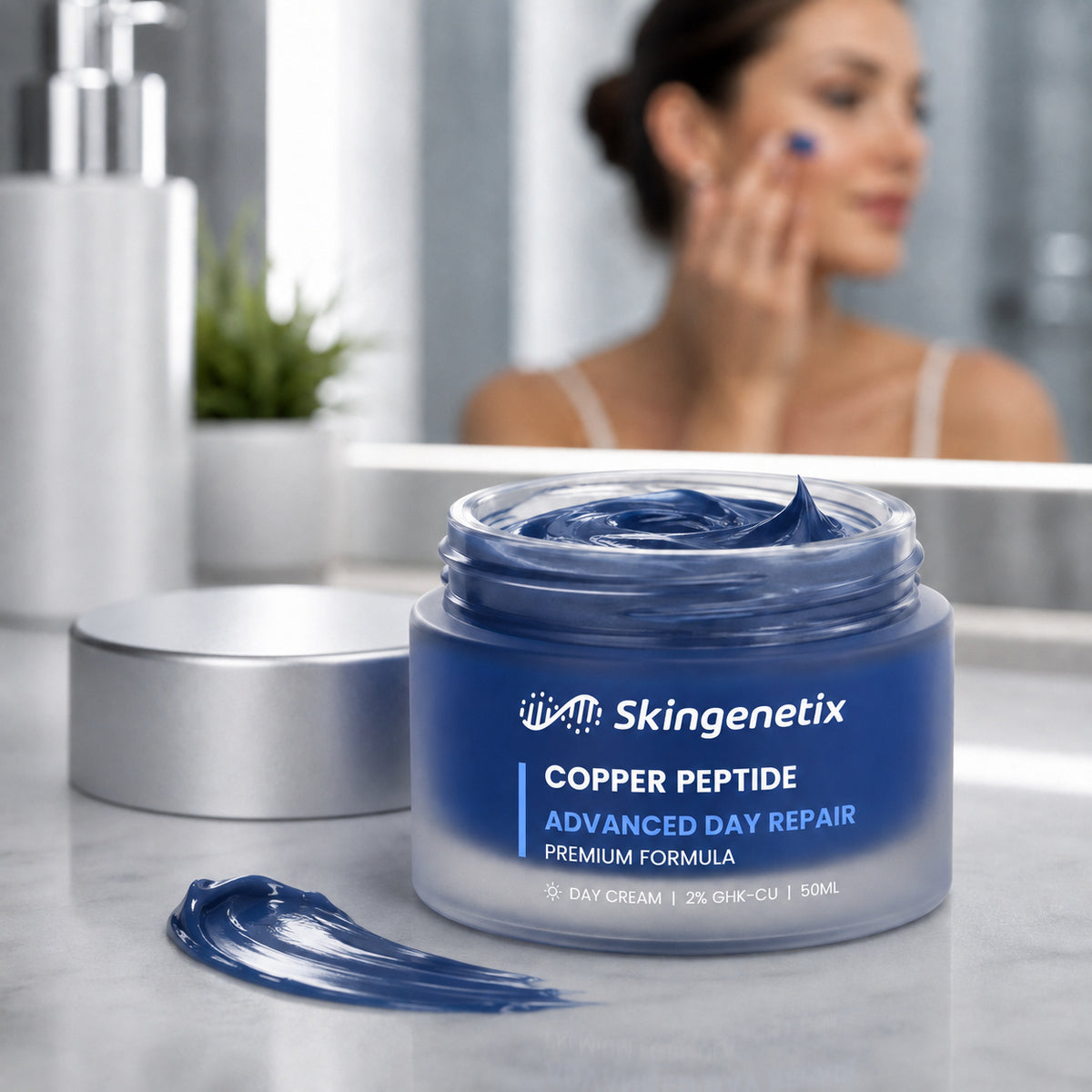 Open jar of Skingenetix Copper Peptide Advanced Day Repair cream on a marble bathroom vanity, a swatch of blue cream beside it and a woman applying it in the background