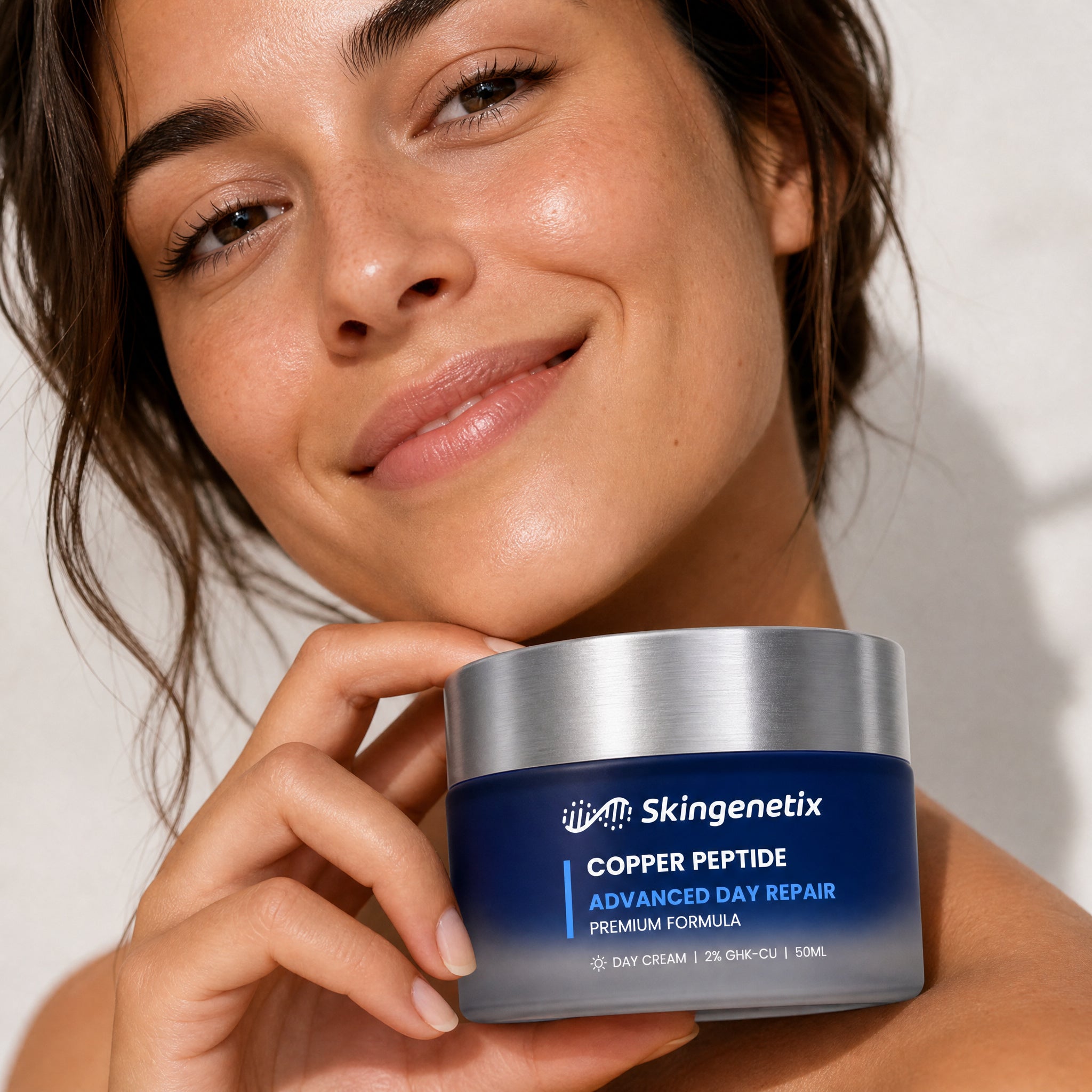 Woman holding a jar of Skingenetix Copper Peptide Advanced Day Repair cream beside her face in natural light