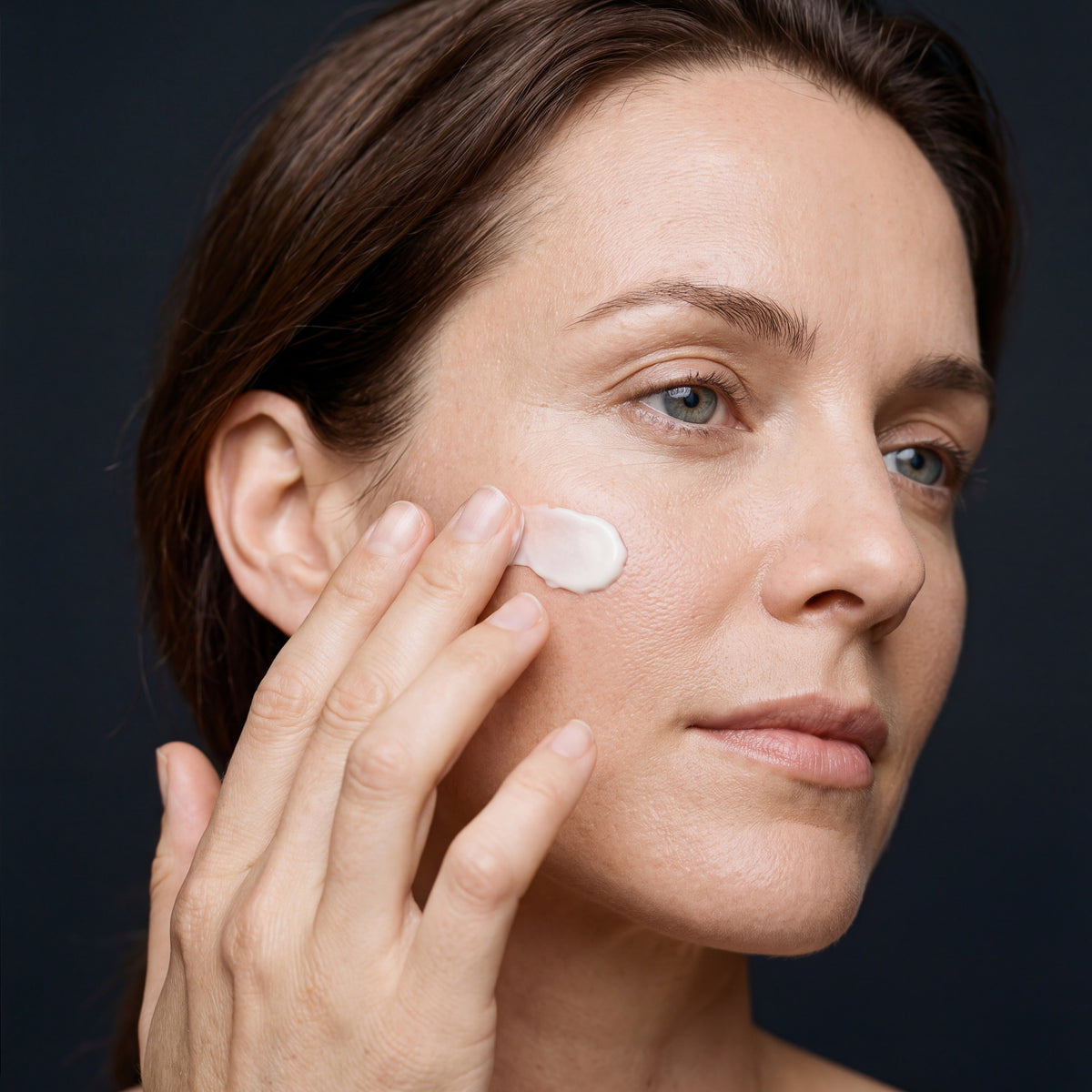 a model applying Skingenetix Matrixyl 3000 Pro Collagen cream to her cheekbone with her fingertips