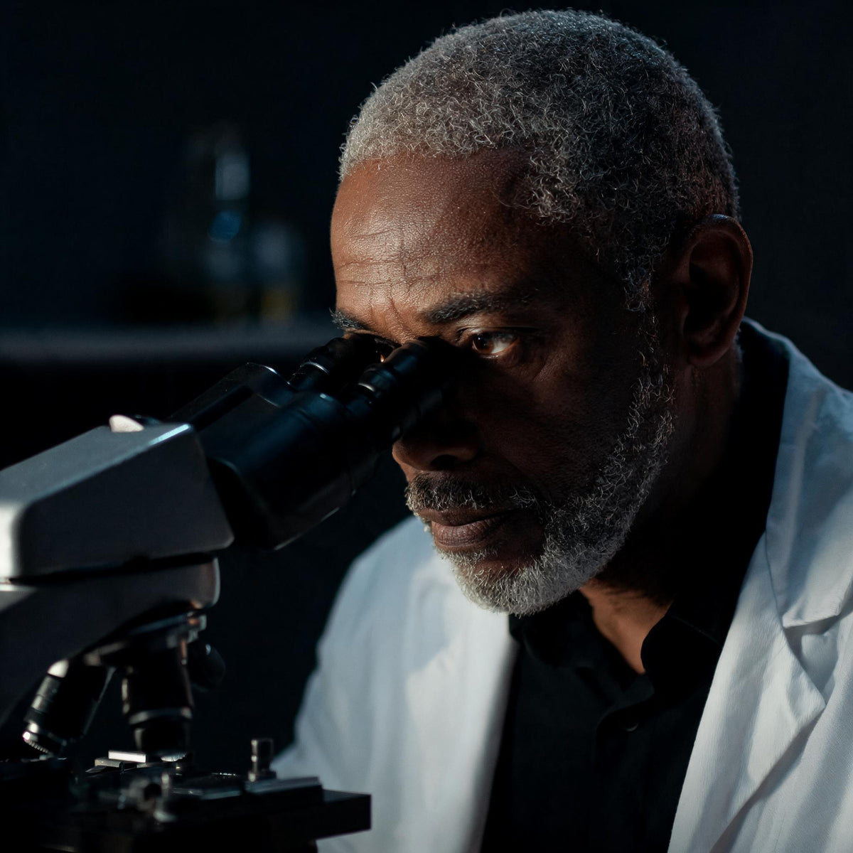 A research scientist examining a sample through a laboratory microscope - Skingenetix scientific research