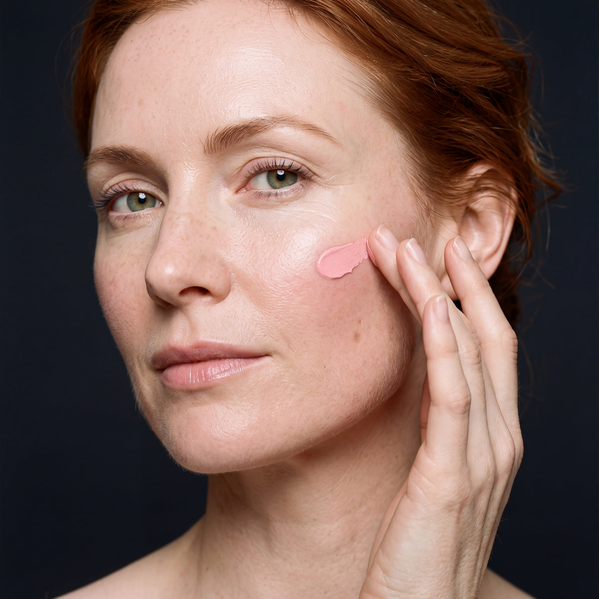 Skingenetix Full PDRN 1% Ritual - Serum & Cream - a woman applying a small swatch of the pink collagen night cream to her cheekbone