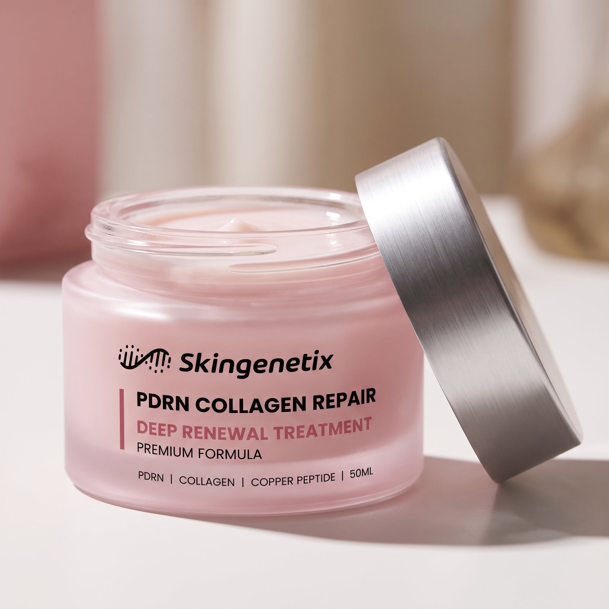 Open frosted pink glass jar of Skingenetix PDRN 1% Collagen Night Cream cream, 50ml, with the brushed silver lid leaning against it on a pale surface