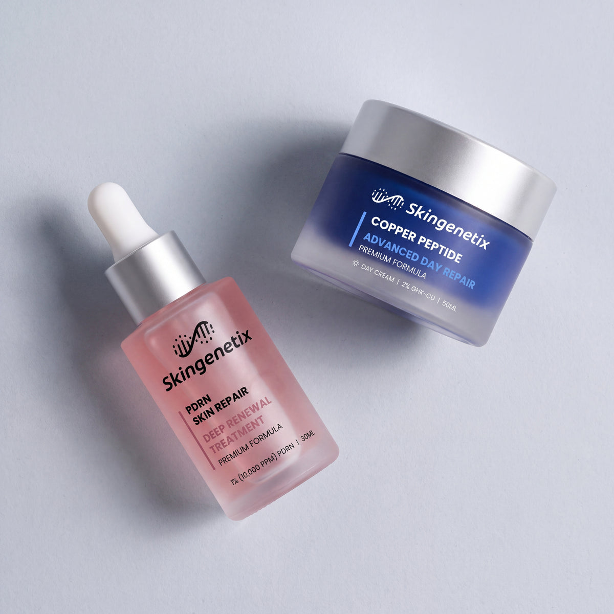 Skingenetix Skin Repair & Renewal Duo Set - the serum and day gel-cream lying tilted on a pale surface