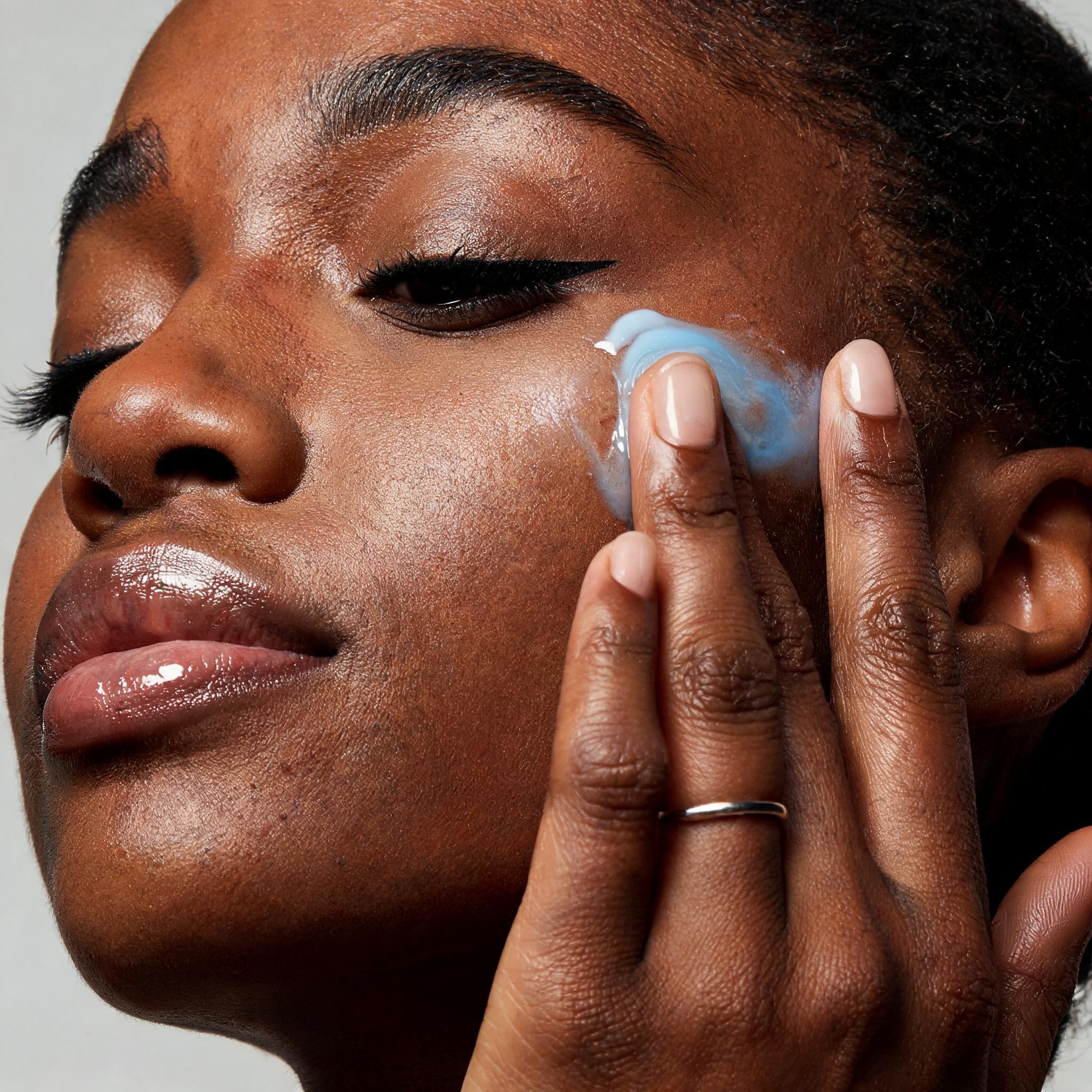 A model with a swatch of blue Copper Peptide serum on her cheek - Skingenetix customer review